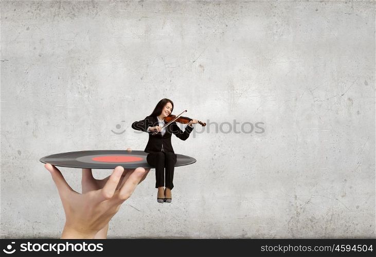 Woman violinist. Young woman sitting on plate and playing violin