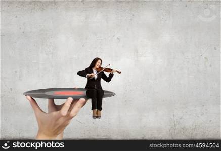 Woman violinist. Young woman sitting on plate and playing violin