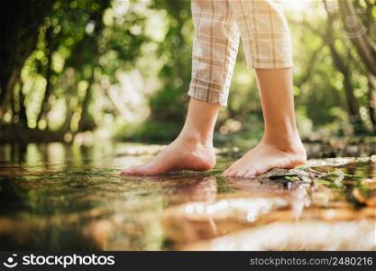 woman wading barefoot in stream in nature forest