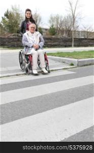 Woman waiting at a zebra crossing with an elderly lady in a wheelchair