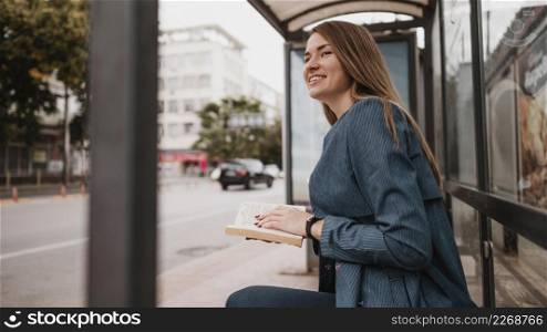 woman waiting bus holding book