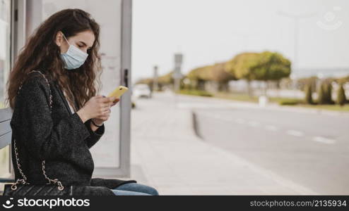 woman waiting bus wearing medical mask