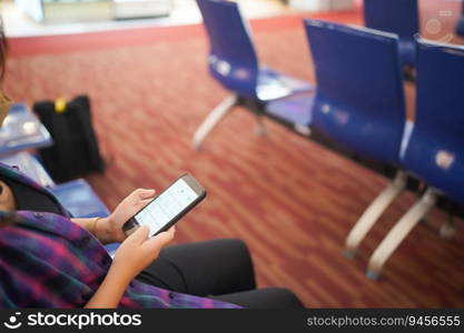 Woman waiting for departure at the airport on your vacation hold passport and smartphone while waiting boarding on departure area International Airport.
