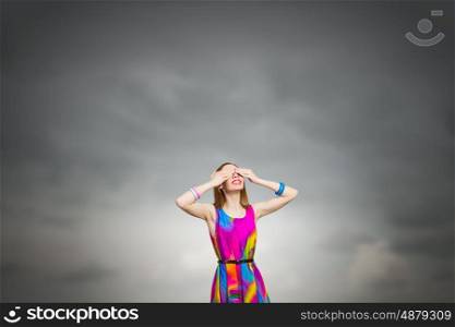 Woman waiting surprise. Young woman in multicolored dress covering eyes with hands