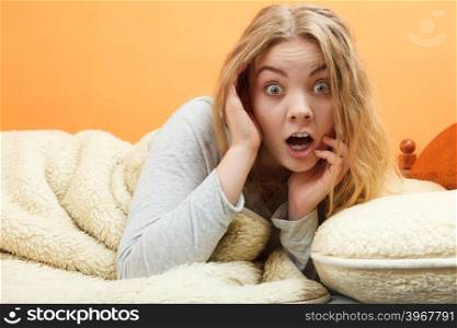Woman waking up in bed in morning after sleeping. Surprised woman waking up in bed in the morning after sleeping. Young girl laying under wool blanket.