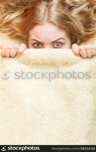 Woman waking up in bed in the morning after sleeping. Well rested young girl laying covering face with wool woolen blanket.