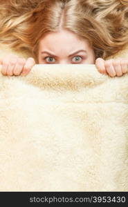 Woman waking up in bed in the morning after sleeping. Well rested young girl laying covering face with wool woolen blanket.