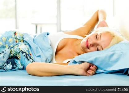 Woman waking up stretching in bed with morning sunshine