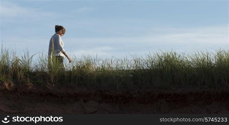 Woman walking along coastline, Green Gables, Cavendish, Prince Edward Island, Canada