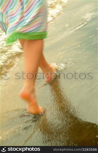 Woman walking along the shore of beach.