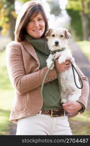 Woman Walking Dog Outdoors In Autumn Park