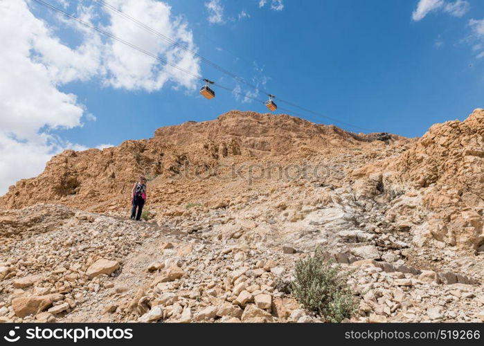 woman walking down the 800 steps of the masada mountain in israel. womam walking from masada mountain