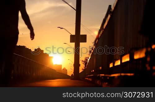 woman walking on a bridge at sunset