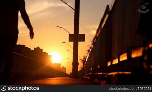 woman walking on a bridge at sunset