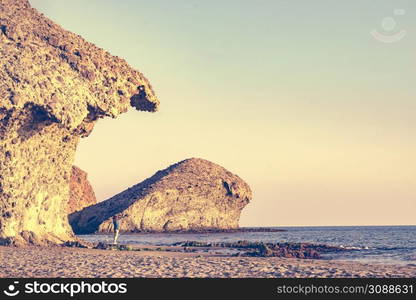 Woman walking on Monsul beach in Cabo de Gata Nijar Natural Park. Coast of Almeria. Huge lava formation as tourist attraction.. People walk on Monsul beach, Park Cabo de Gata, Spain