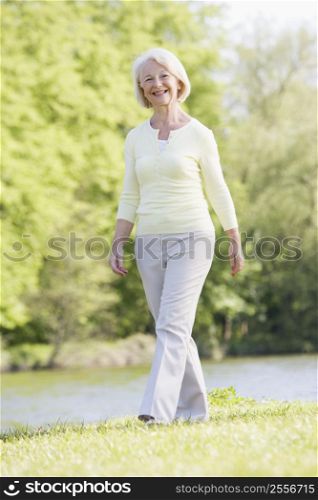 Woman walking outdoors at park by lake smiling
