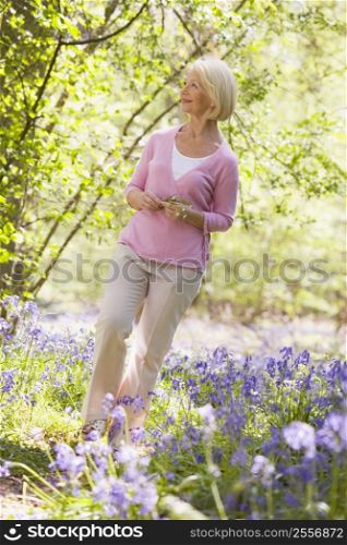 Woman walking outdoors holding flower smiling