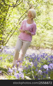 Woman walking outdoors holding flower smiling