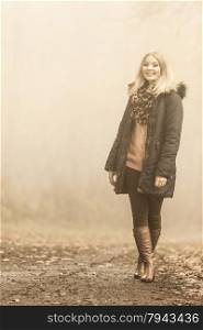 Woman walking relaxing in foggy day in romantic autumn forest park outdoor, tinted aged photo