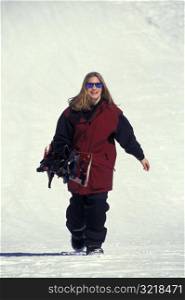 Woman Walking Through Snow Carrying Snowboard