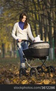 Woman walking with baby in pram in park