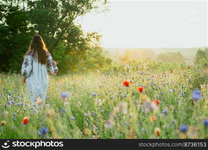Woman walks in cornflower meadow scenic photography. Field in bloom. Picture of lady with beautiful nature on background. High quality wallpaper. Photo concept for ads, travel blog, magazine, article. Woman walks in cornflower meadow scenic photography