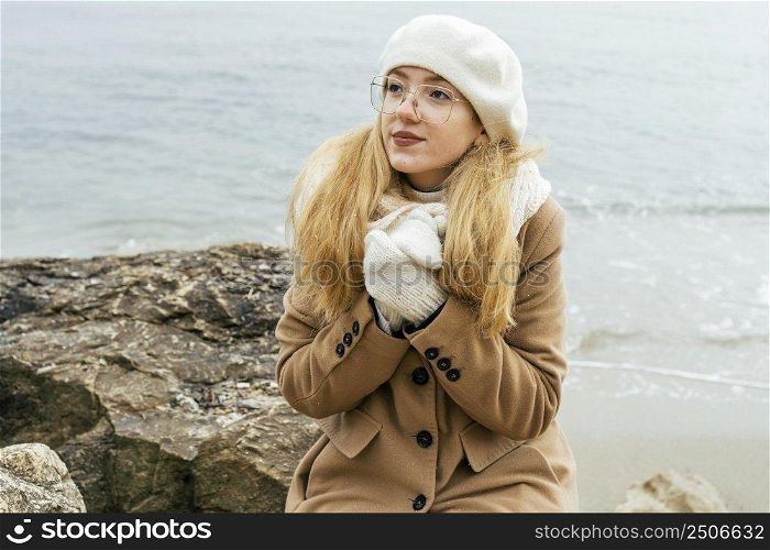 woman warming her hands beach during winter
