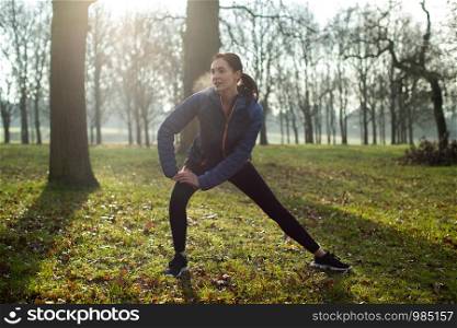 Woman Warming Up For Morning Exercise With Stretches In Winter Park