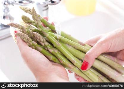Woman Washing Asparagus in the Kitchen Sink.