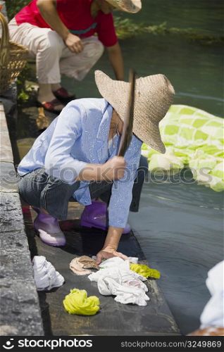Woman washing clothes at riverside, Xidi, Anhui Province, China