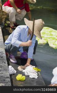 Woman washing clothes at riverside, Xidi, Anhui Province, China