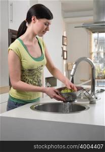 Woman washing grapes in kitchen sink