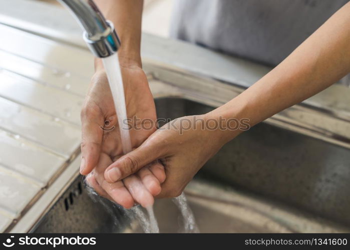 Woman washing hand in the kitchen at home