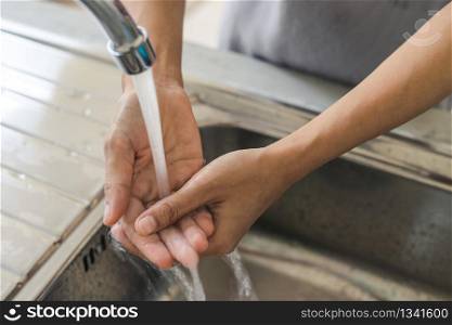 Woman washing hand in the kitchen at home