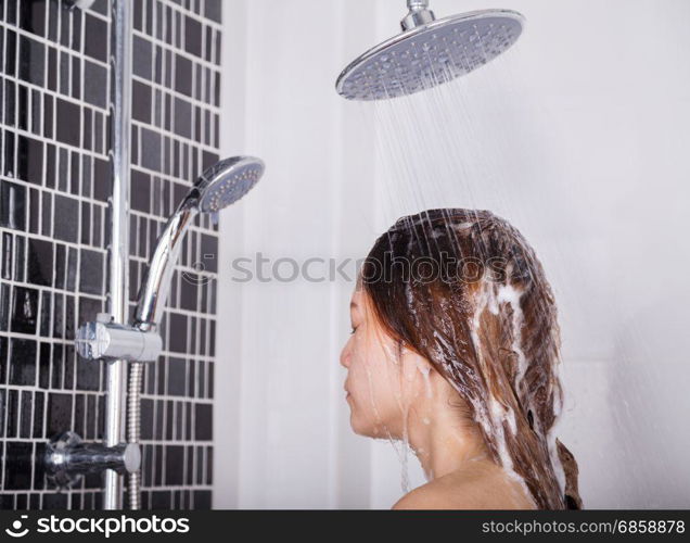 woman washing her head and hair in the rain shower by shampoo