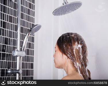 woman washing her head and hair in the rain shower by shampoo