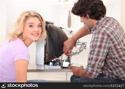 Woman watching husband fix television