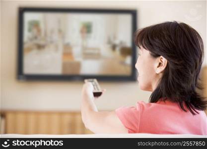 Woman watching television using remote control