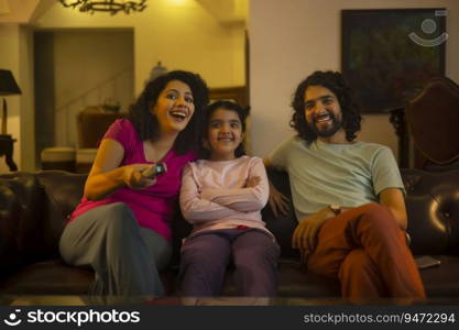 Woman watching television with her daughter and husband and holding remote