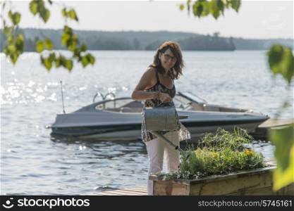 Woman watering plants on a dock, Lake of The Woods, Ontario, Canada