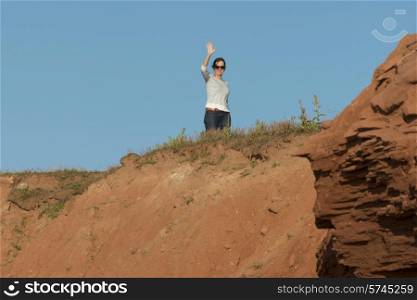 Woman waving from top of rocky cliff, Green Gables, Cavendish, Prince Edward Island, Canada