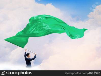 Woman waving green flag. Determined businesswoman waving flag as symbol of power