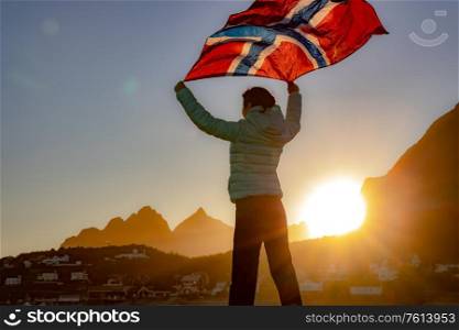 Woman waving the flag of Norway at sunset background