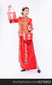 Woman wear Cheongsam suit and black shoe glad getting red bag for surprising in chinese new year