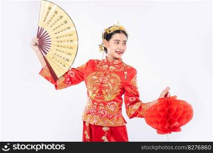 Woman wear Cheongsam suit hold the chinese hand fan and red l&to show on big event in chinese new year