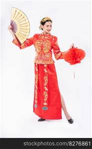 Woman wear Cheongsam suit hold the chinese hand fan and red l&to show on big event in chinese new year