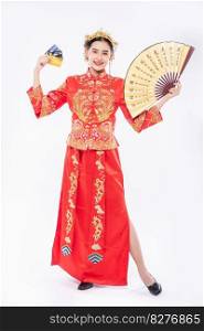 Woman wear Cheongsam suit hold the chinese hand fan and show the credit caard can be use on event in chinese new year