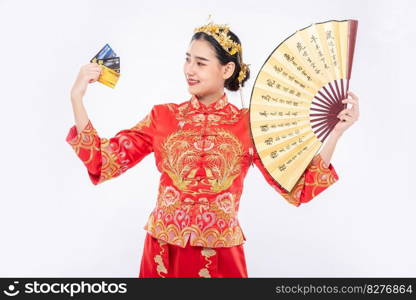 Woman wear Cheongsam suit hold the chinese hand fan show the credit card can be use to shopping in chinese new year