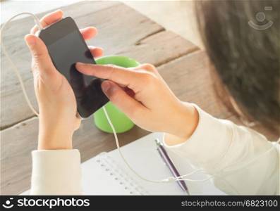 Woman wear headphones surfing the net by smart phone, stock photo