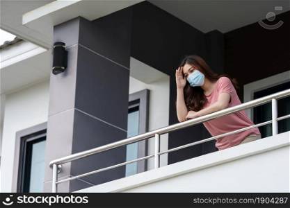 woman wearing a face mask and quarantine in balcony of her home, coronavirus (covid-19) pandemic concept